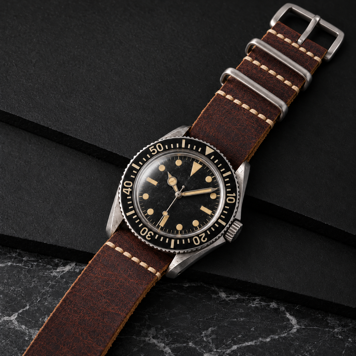 Brown leather strap on a vintage-style watch against dark slate